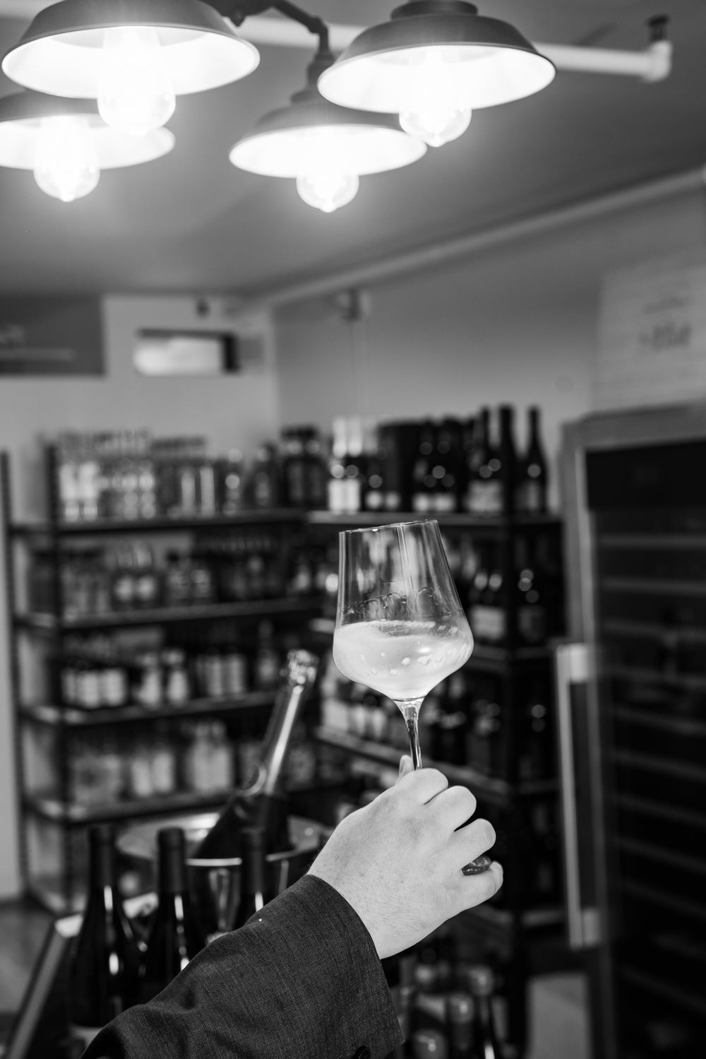 A glass of white wine held up inside Pure Wine